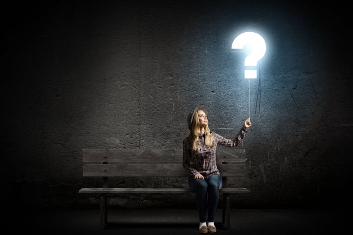 women sitting under a light question mark