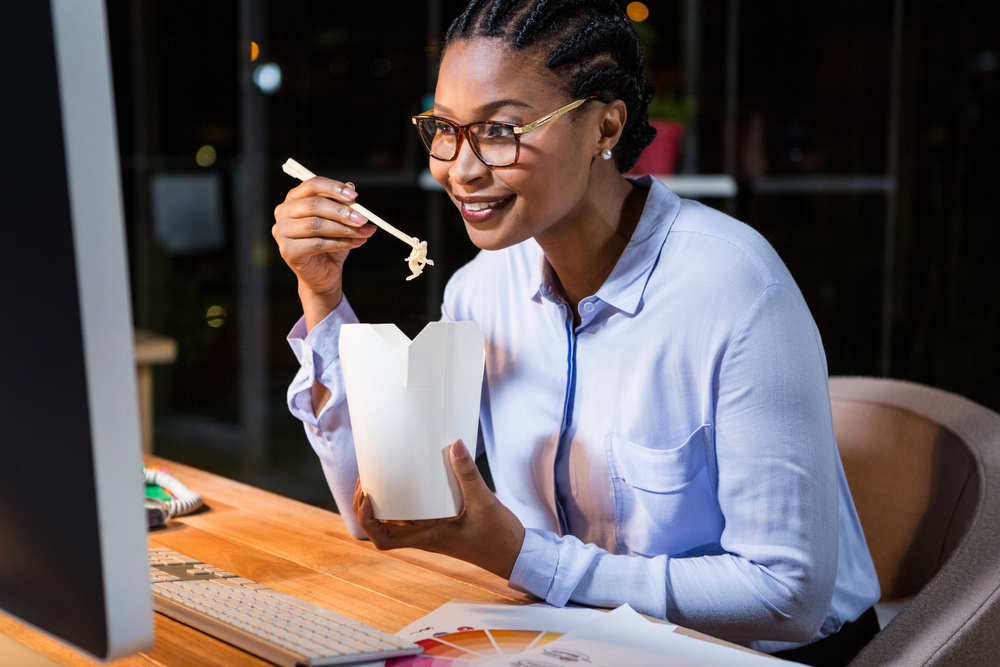 Businesswoman eating noodles at her desk in the office