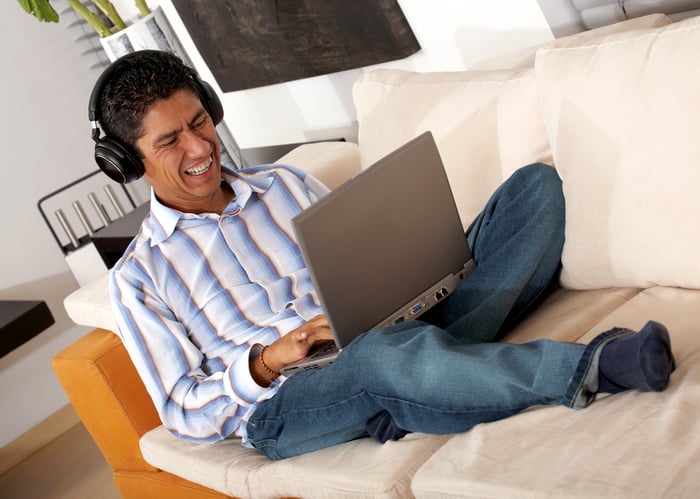 man at home downloading music on a laptop computer